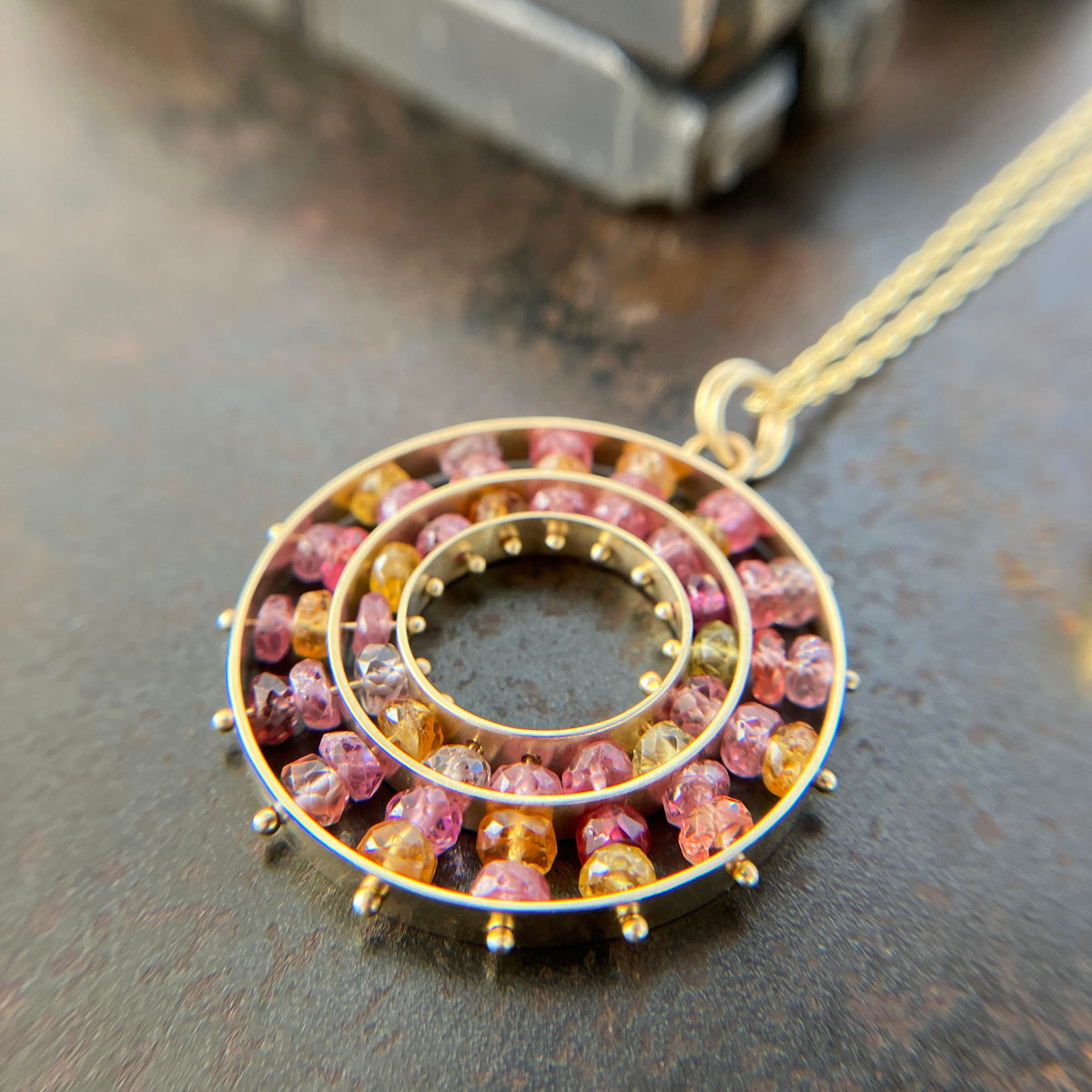 sapphire bead pendant with concentric circles of 14k gold