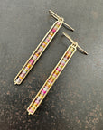 14k Gold bar earrings with colorful sapphire gemstones on a dark surface