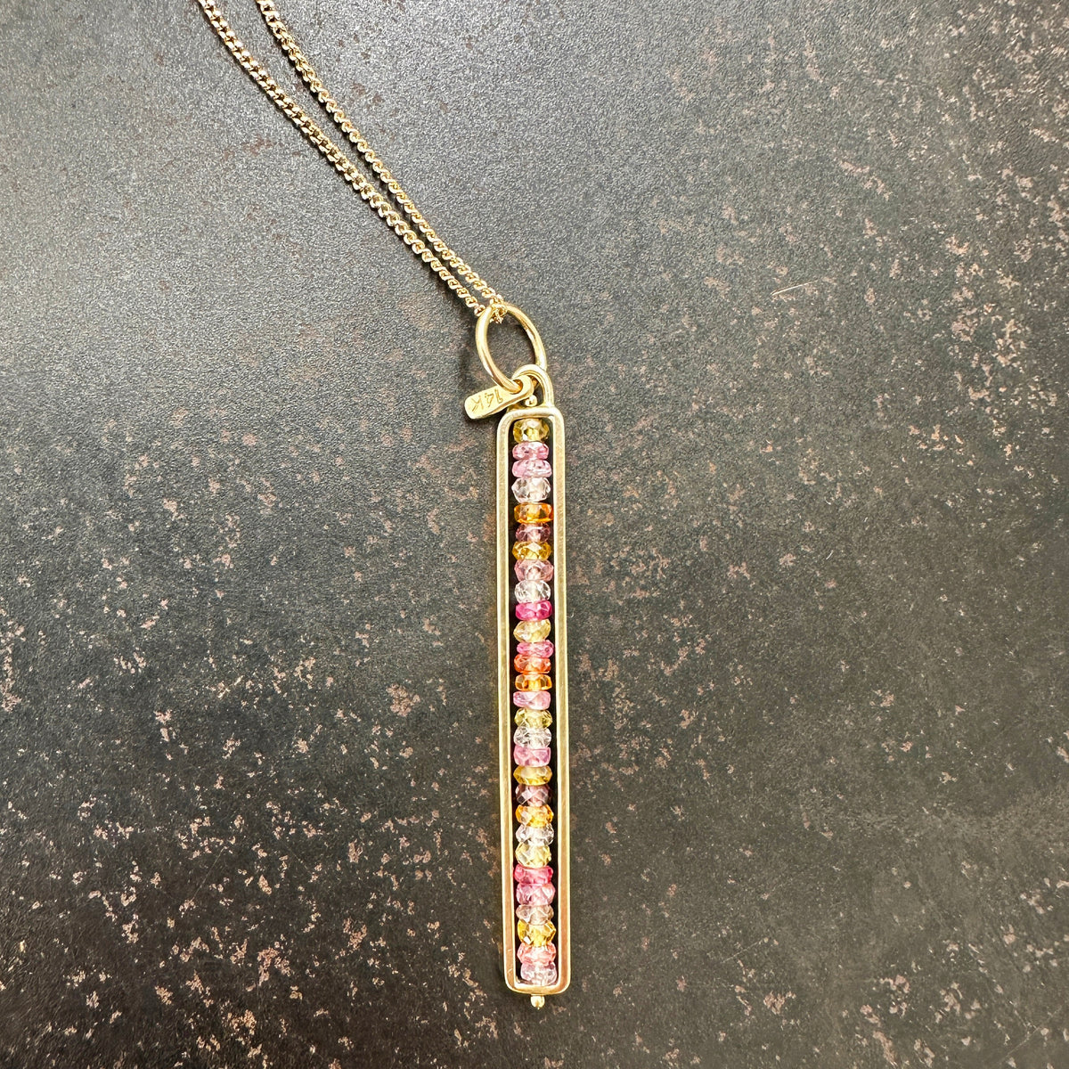 Necklace with a colorful sapphire beaded pendant on a dark surface