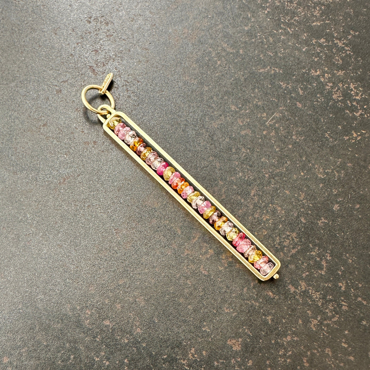 Necklace with a colorful sapphire beaded pendant on a dark surface