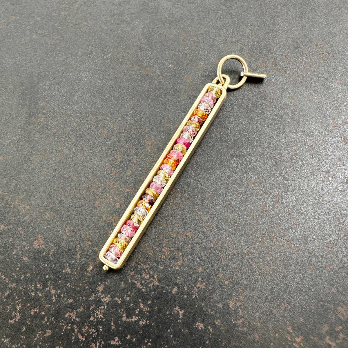 Necklace with a colorful sapphire beaded pendant on a dark surface