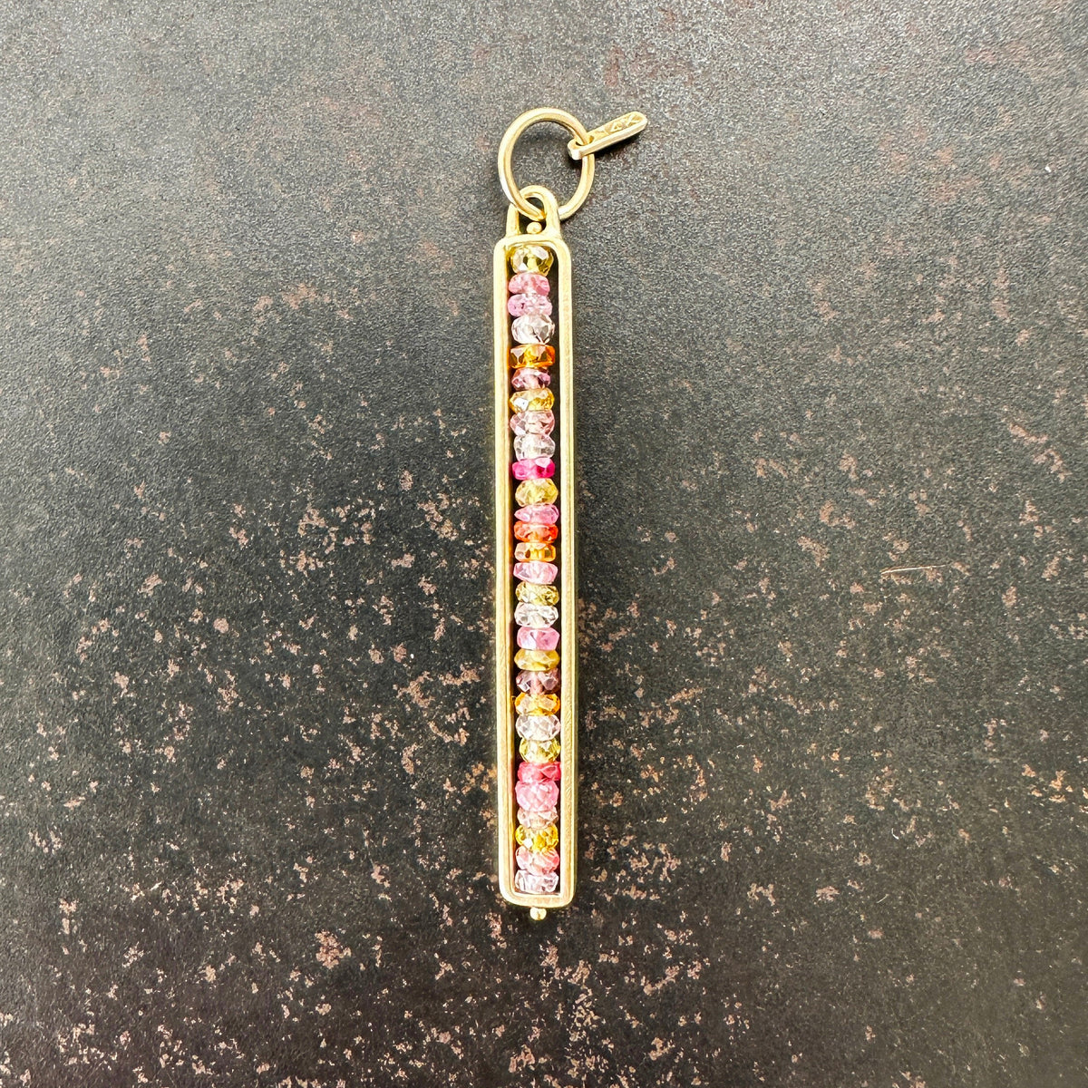 Necklace with a colorful sapphire beaded pendant on a dark surface
