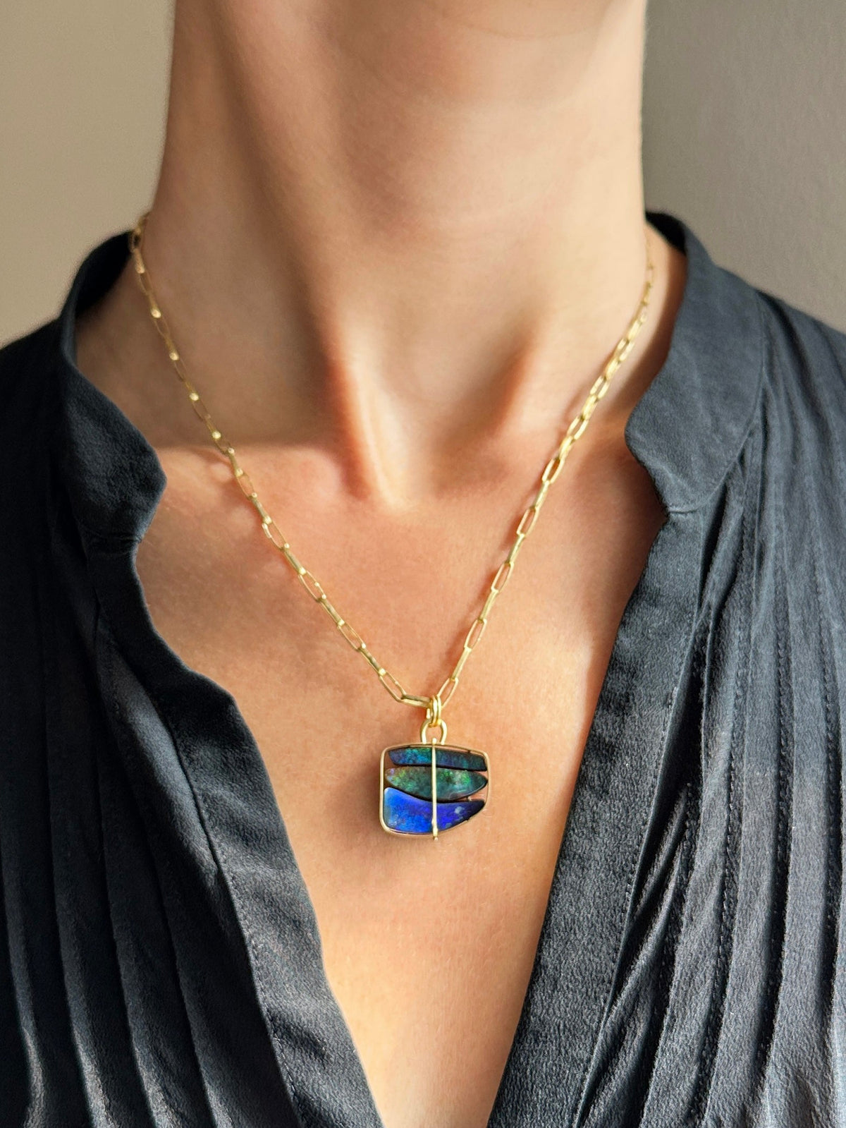 blue and green boulder opal pendant in 18k gold on a model