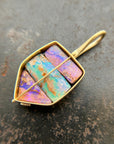 A shield-shaped pendant featuring an 18k gold frame and three rectangular inlay wood replacement opals in pink, turquoise, purple, and brown.
