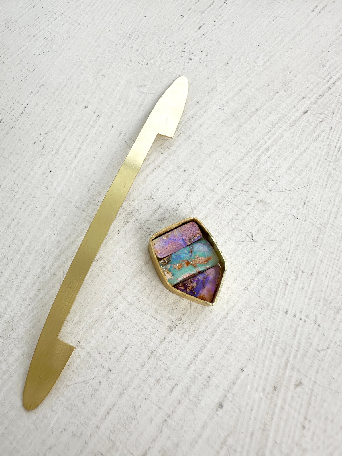 A shield-shaped pendant featuring an 18k gold frame and three rectangular inlay wood replacement opals in pink, turquoise, purple, and brown.