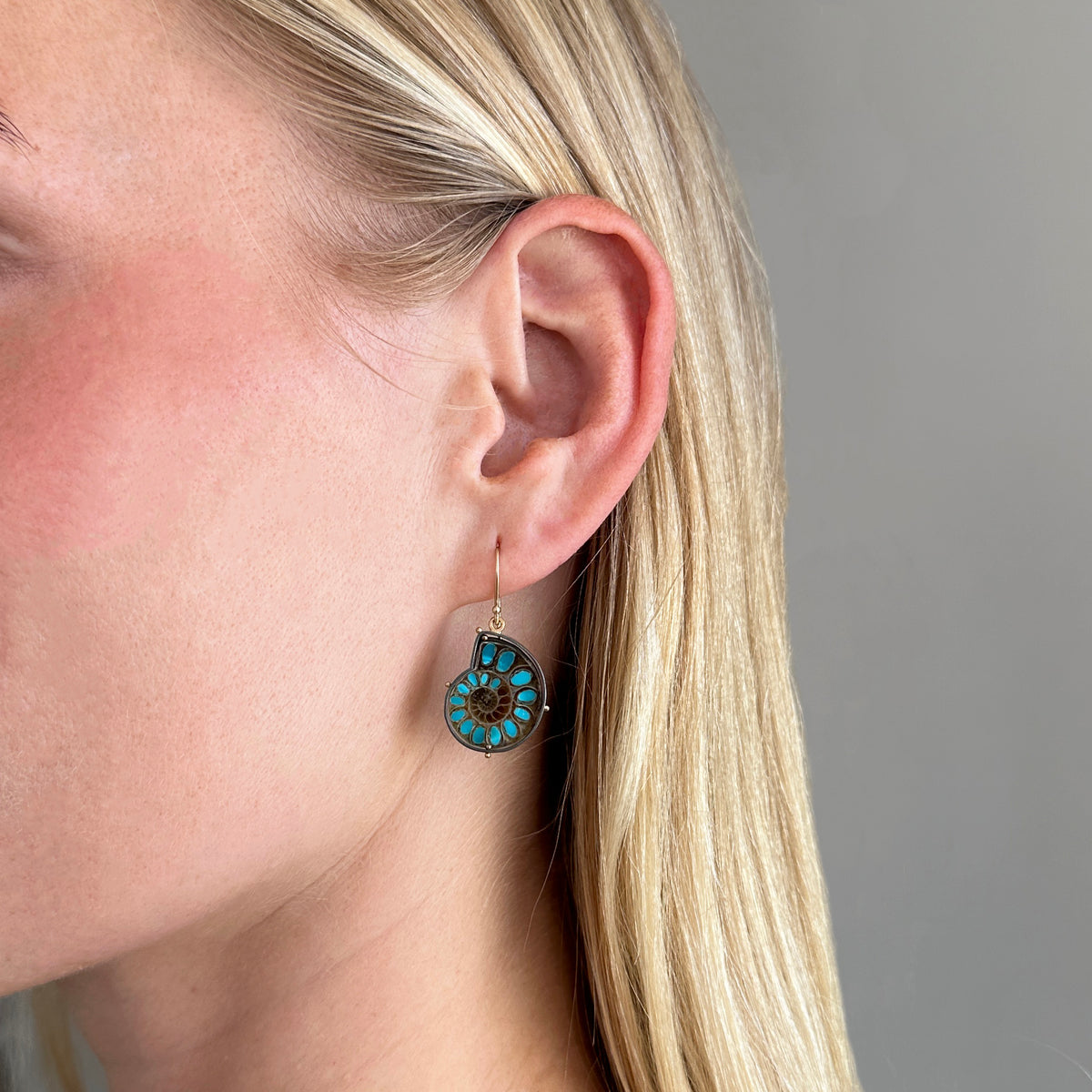 model wearing ammonite with embedded turquoise earrings in silver and gold on gold hooks