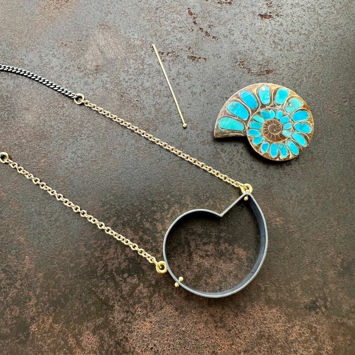 process photo of ammonite with embedded turquoise necklace in silver and gold on silver and gold chain