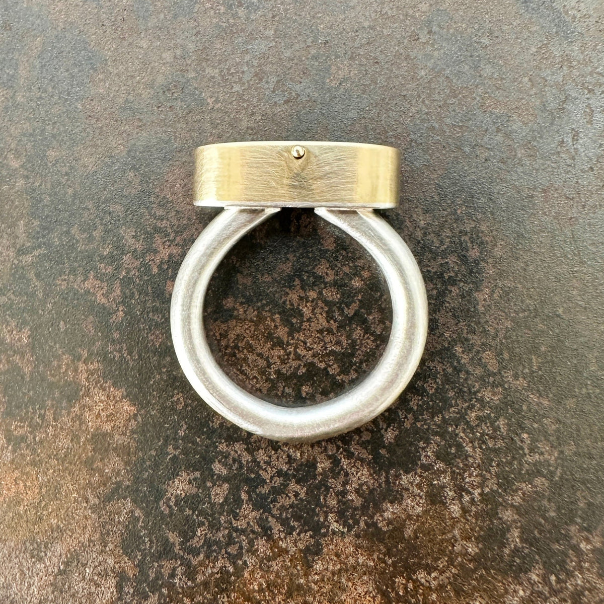 Silver and gold ring with a turquoise stone on a gray surface