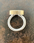 Silver and gold ring with a turquoise stone on a gray surface