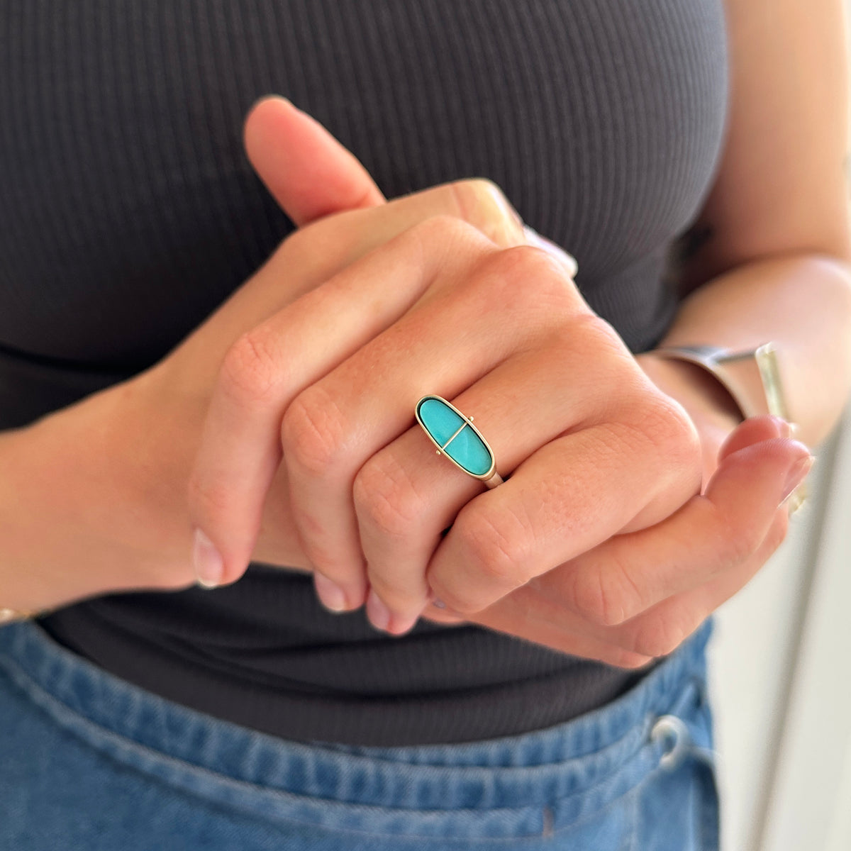 Silver and gold ring with a turquoise stone on a gray surface