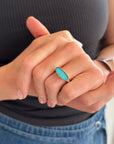 Silver and gold ring with a turquoise stone on a gray surface