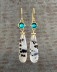 Pair of earrings with teardrop-shaped montana agates and turquoise with 18k gold on a textured gray background
