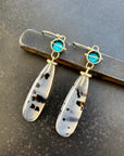 Pair of earrings with teardrop-shaped montana agates and turquoise with 18k gold on a textured gray background